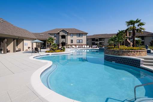 A large swimming pool in front of a building with a clear blue sky.