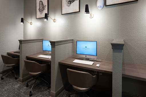 Two computers are on desks with chairs in front of them.