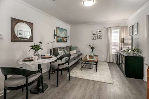 A living room with a grey sofa, a coffee table, and a dining table with chairs.