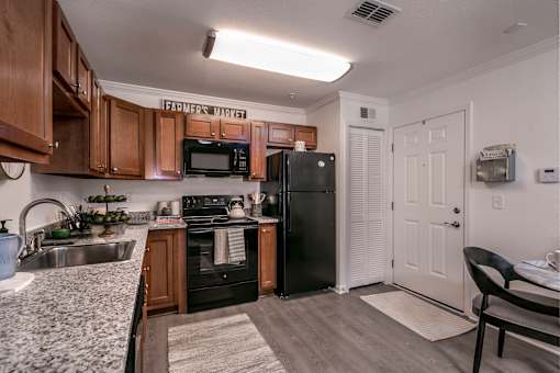 A kitchen with a black refrigerator and wooden cabinets.