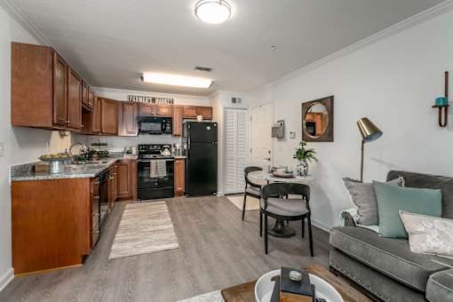 A kitchen with a black fridge and a grey couch.