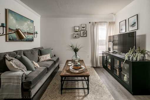 A living room with a grey couch, a coffee table, and a painting on the wall.