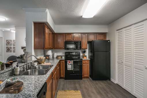 A kitchen with a black refrigerator and wooden cabinets.