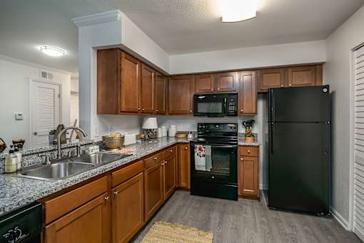 A kitchen with black appliances and wooden cabinets.