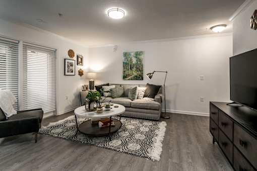 A living room with a grey couch, a coffee table, and a painting on the wall.