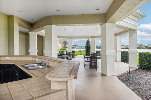 a large porch with a sink and a patio with tables and chairs