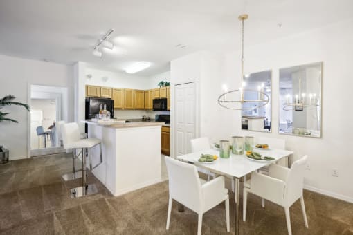 a dining room and kitchen with a white table and chairs
