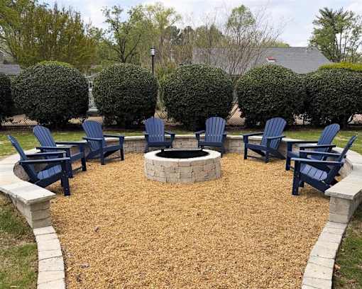 A fire pit surrounded by blue chairs in a backyard.