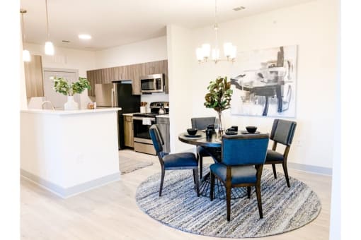 a dining area with a table and chairs and a kitchen in the background