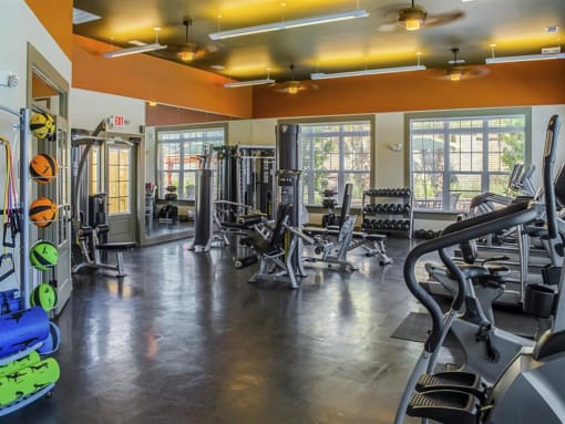 a gym with cardio equipment and windows