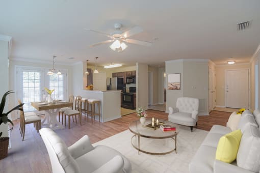 a living room and kitchen with white furniture and a ceiling fan at 10X Audubon Park apartments in Daphne, AL 