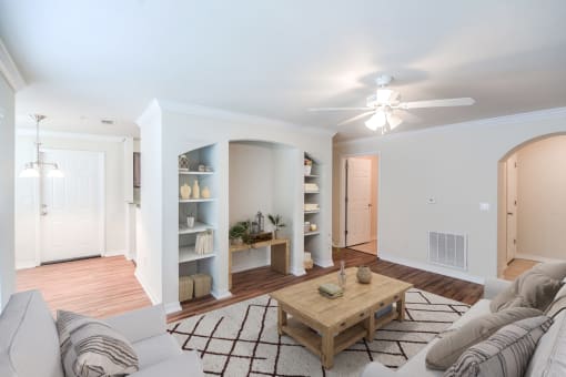 A living room with a couch, coffee table, and a ceiling fan at 10X Audubon Park apartments in Daphne, AL 