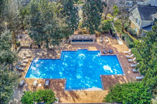 a view of the pool from above   the pool is surrounded by trees at 10X Audubon Park apartments in Daphne, AL 