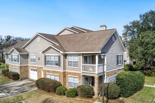 the front of a house with bushes and trees at 10X Audubon Park apartments in Daphne, AL 