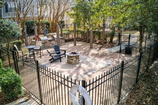 A black fenced in area with a fire pit and chairs at 10X Audubon Park apartments in Daphne, AL 