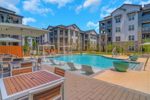 an outdoor pool with tables and chairs at an apartment building