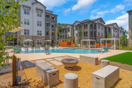 an outdoor swimming pool with outdoor game space and cabanas at Tapestry Overbrook in McDonough, Georgia