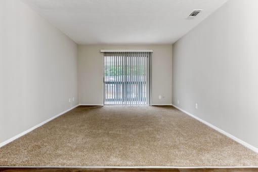 a spacious bedroom with a sliding glass door and carpeted flooring