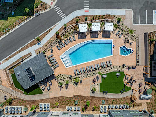 An aerial view of a swimming pool surrounded by lounge chairs and umbrellas.