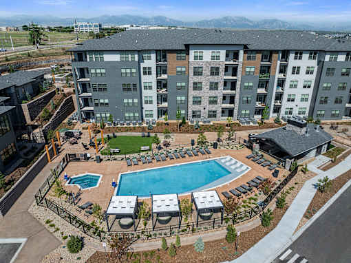 A large apartment complex with a pool and a mountain range in the background.