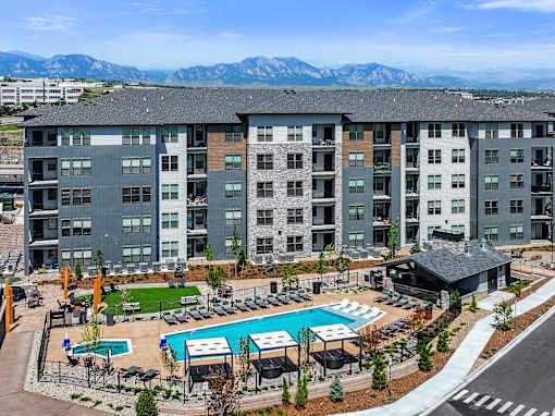 A large apartment complex with a pool and a view of the mountains.