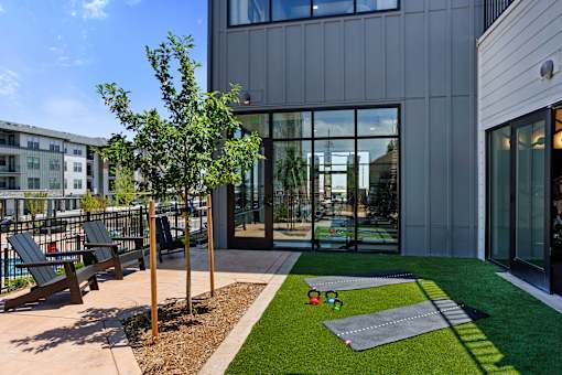 A modern building with a grey exterior and a small garden area in front.