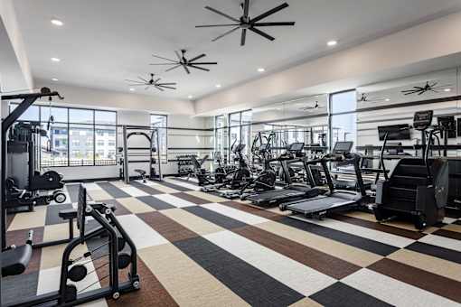 A gym with a variety of equipment including treadmills, weights, and exercise machines.