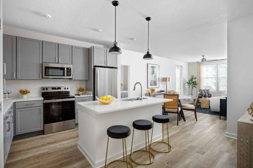 A modern kitchen with a white island and stools.
