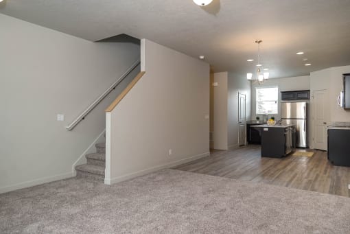 Carpeted room with staircase at The Village at Church & Main, Layton