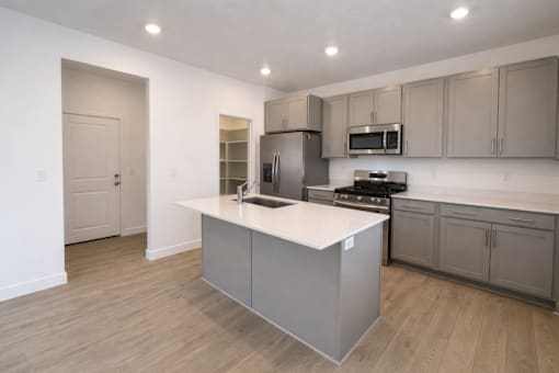 A kitchen with a white countertop and grey cabinets.