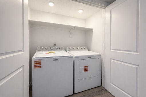 Two white washing machines in a small laundry room.