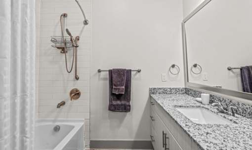 Bathroom with granite countertop and subway tile shower at Avion at West Lemmon Apartments, Dallas, TX