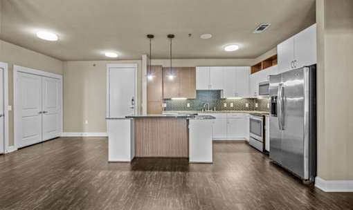 Open kitchen with island and stainless steel appliances at Matilda at Lower Greenville Apartments, Dallas