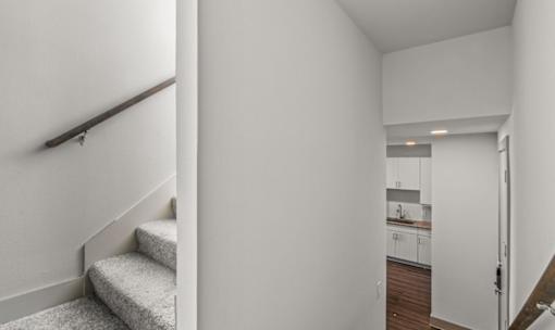 Interior hallway with staircase and kitchen view at Avion at West Lemmon Apartments, Dallas, Texas