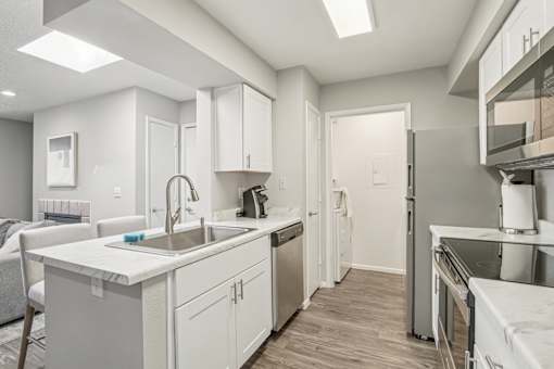 A modern kitchen with white cabinets and stainless steel appliances.