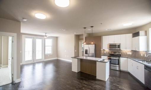 Open concept living and kitchen with dark wood flooring at Matilda at Lower Greenville Apartments, Dallas, Texas