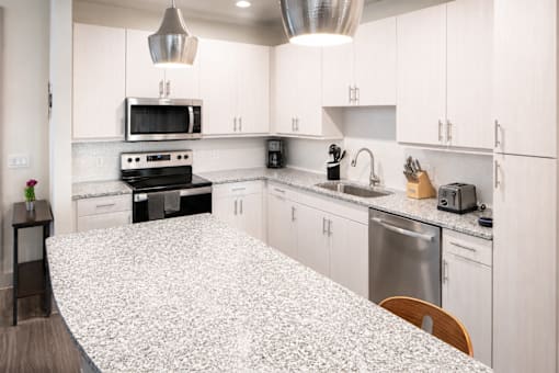 Modern kitchen with white cabinets and granite countertops at Avion at West Lemmon Apartments, Dallas, TX 75235