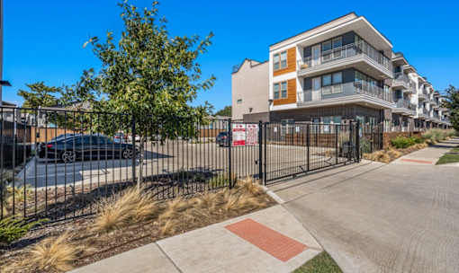 Modern apartment building with secured parking area at Avion at West Lemmon Apartments, Dallas, TX