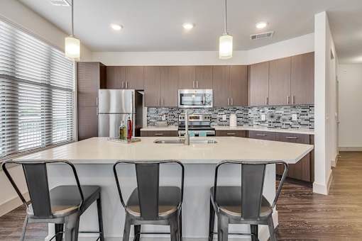 A modern kitchen with a white island and chairs.