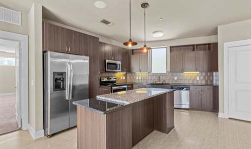 Kitchen with island bar and wood grain cabinetry at Matilda at Lower Greenville Apartments, Texas, 75206