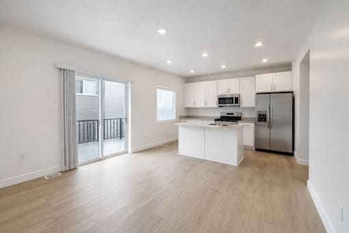 A spacious kitchen with white cabinets and a refrigerator.