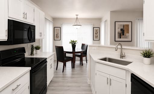 Modern kitchen with white cabinets and black appliances at Cortina Apartments, Phoenix, AZ