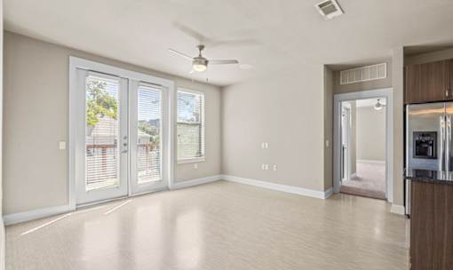 Bright living room with french doors and ceiling fan at Matilda at Lower Greenville Apartments, Dallas, TX 75206