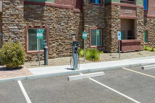A parking lot with a charging station and a building in the background.