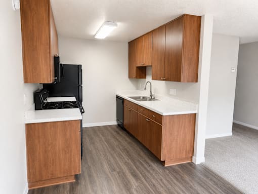 A kitchen with wooden cabinets and a black fridge.