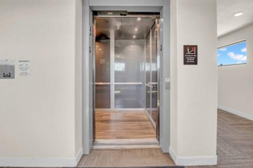 A hallway with a glass door and a brown floor.