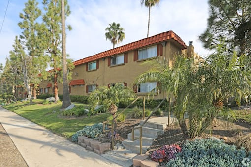 A house with a red tile roof is surrounded by greenery.