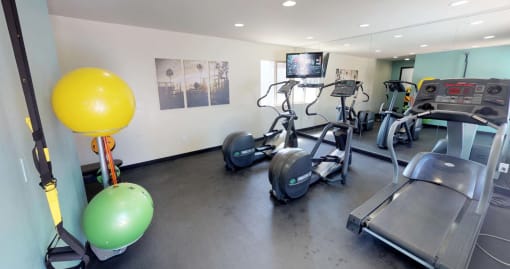 Stationary bikes, treadmill reflected in mirrored wall of fitness center