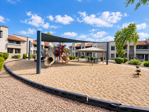 Community playground with shade canopy and sand surface at Gentrys Walk Apartments, Mesa, 85204