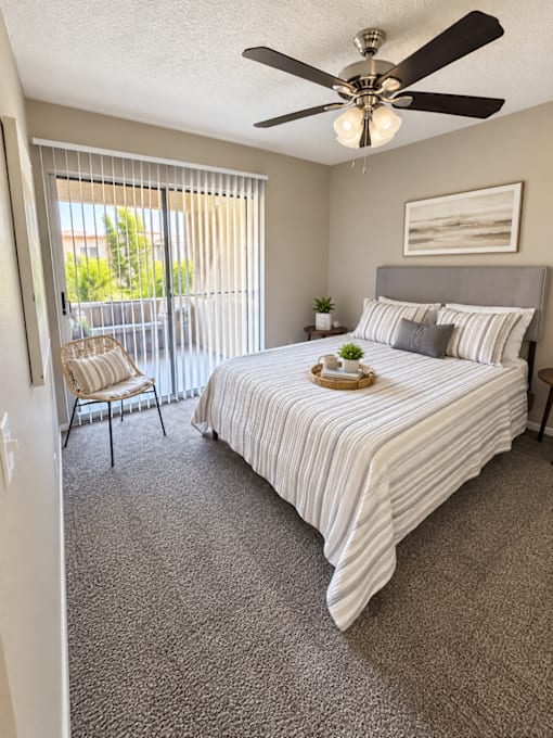 Bedroom with balcony access and ceiling fan at Gentrys Walk Apartments, Mesa